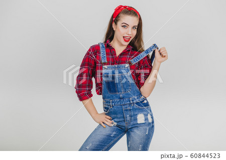 Cute girl standing, pulling up her suspender, keeping one hand on her hip, looking seducively at the camera. 60844523