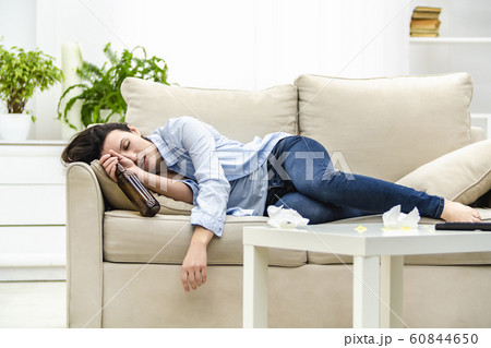 Unconscious drunk woman with empty bottle in her hand is sleeping on the sofa. 60844650