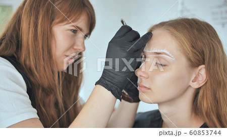 Permanent makeup. Permanent tattooing of eyebrows. Cosmetologist applying permanent make up on eyebrows - eyebrow tattoo. Permanent makeup. Permanent tattooing of eyebrows. Cosmetologist applying permanent make up on eyebrows - eyebrow tattoo. 60853744