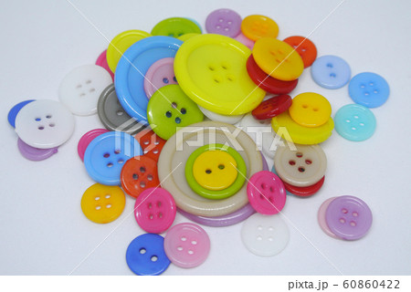 Colourful and various size of cloth button inside clear plastic container isolated on white background  60860422