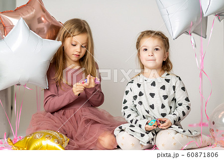 two blonde little sisters play sitting on the floor in a photo studio 60871806