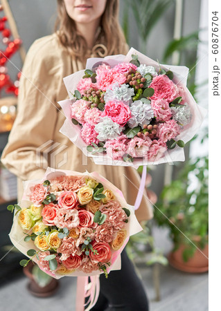 European floral shop. Two Beautiful bouquets of mixed flowers in womans hands. the work of the florist at a flower shop. Delivery fresh cut flower. 60876704