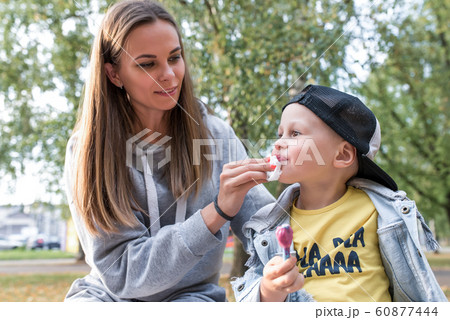 mother son, eat ice cream, wipe lips and face of child with napkin, care for her son, summer day park autumn, support for love happiness weekend. Rest with parent nature. Emotions purity hygiene. 60877444