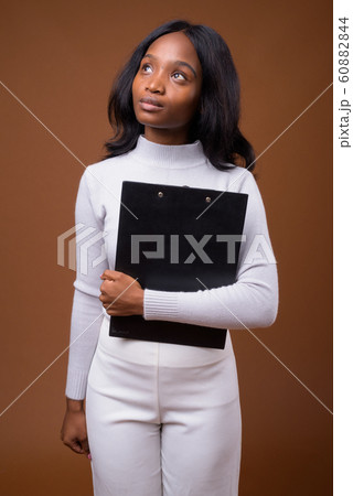 Young beautiful African Zulu businesswoman against brown backgro 60882844