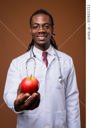 Young handsome African man doctor against brown background 60883251
