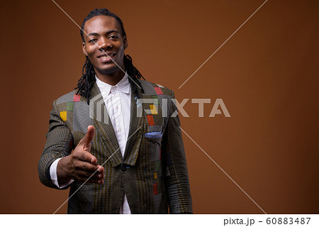 Young handsome African businessman against brown background 60883487