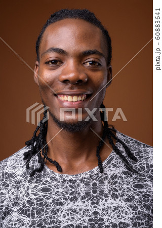 Young handsome African man against brown background 60883641