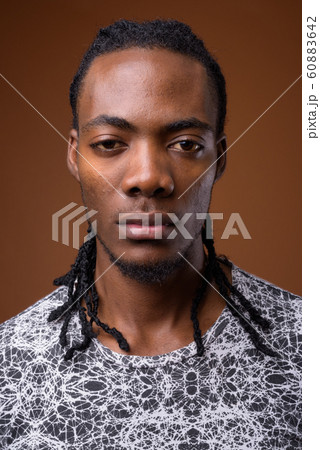 Young handsome African man against brown background Young handsome African man against brown background 60883642