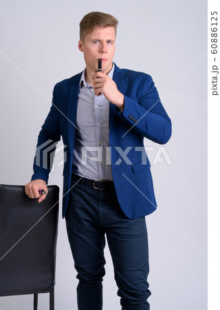Young handsome blonde businessman smoking pipe while holding chair 60886125