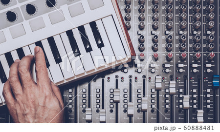 musician hand playing midi keyboard on audio mixing console 60888481