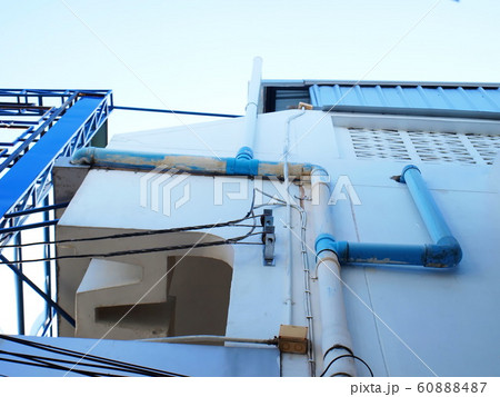Drain pipe beside the building wall PVC pipe for rainwater and water drainage On the background of buildings and blue skies. Selective focus 60888487
