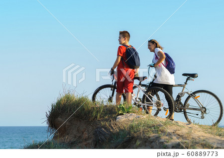 boy and young woman on a Bicycle on a cliff by the sea 60889773