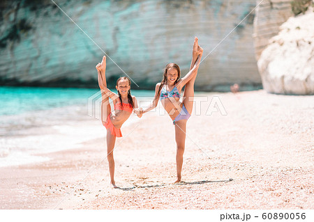 Adorable little girls have fun together on white tropical beach Adorable little girls have fun together on white tropical beach 60890056