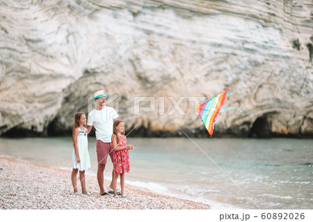 Family flying kite together at tropical white beach 60892026
