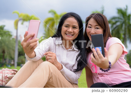 Two mature Asian women together relaxing at the park 60900290