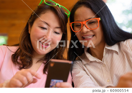 Two mature Asian women together hanging out at the coffee shop Two mature Asian women together hanging out at the coffee shop 60900554