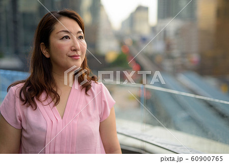 Mature Asian woman against view of the city Mature Asian woman against view of the city 60900765