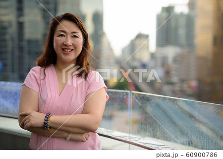 Mature Asian woman against view of the city 60900786