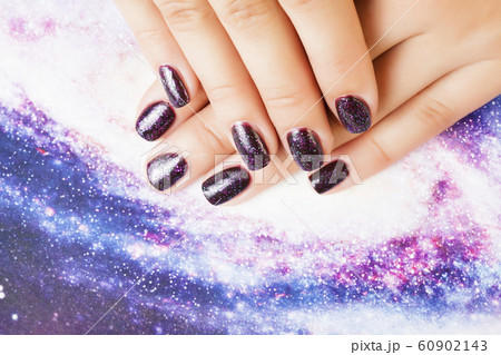 manicure stylish concept: woman fingers with nails purple glitter on nails like cosmos, universe background manicure stylish concept: woman fingers with nails purple glitter on nails like cosmos, universe background 60902143