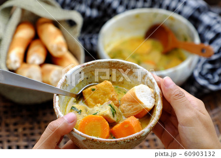 People eating delicious yellow vegan curry dish bowl with bread for breakfast 60903132
