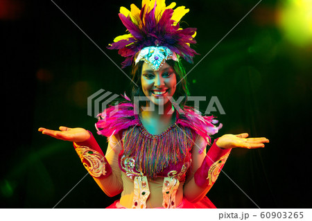 Beautiful young woman in carnival mask and masquerade costume in colorful lights Beautiful young woman in carnival mask and masquerade costume in colorful lights 60903265