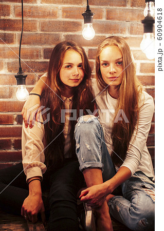two teenage girl friends together having fun in modern loft interior with holiday lights, lifestyle people concept 60904618