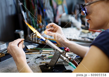 Woman artist making glass jewelry in her workshop Woman artist making glass jewelry in her workshop 60905558