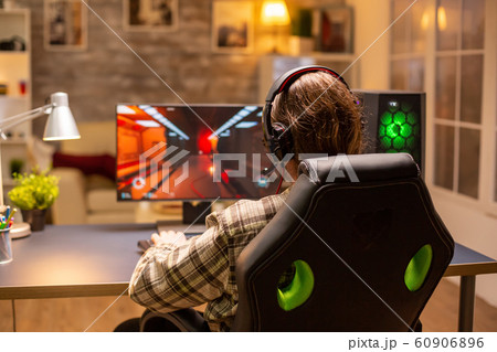 Back view of gamer male playing a shooter on his powerful PC computer late at night in the living room 60906896