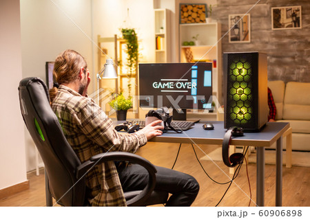 Man on his powerful PC computer in the living room late at night loosing a game 60906898