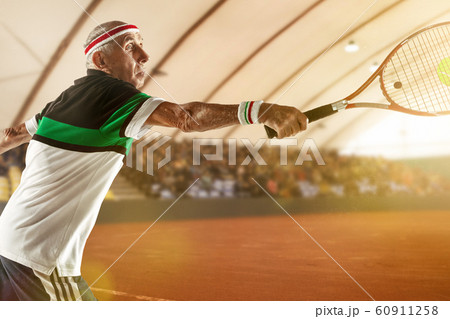 Senior man playing tennis in sportwear on stadium 60911258