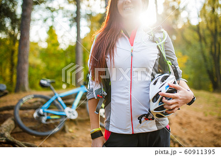 Photo of young sporty woman with helmet on background of bicycle at autumn forest Photo of young sporty woman with helmet on background of bicycle at autumn forest 60911395