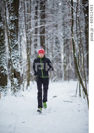 Photo of running athlete among trees in winter forest Photo of running athlete among trees in winter forest 60911493