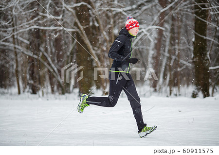 Image from side of man in sportswear, red cap on run in winter 60911575