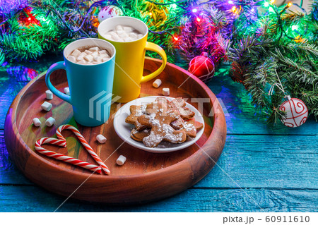 Image of New Year cookies, cookies, two mugs of cocoa with marshmallows, caramel sticks, branches of spruce 60911610