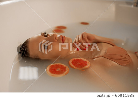 Sexy young woman with perfect skin in a bath with milk and circles of grapefruit 60911938