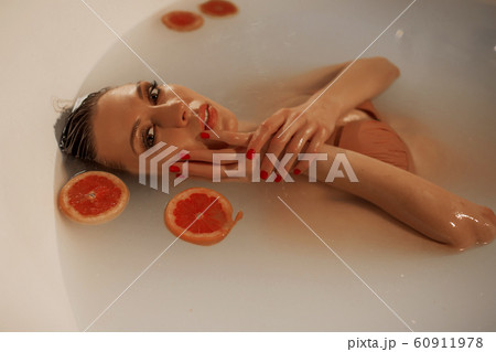 Sexy young woman with perfect skin in a bath with milk and circles of grapefruit 60911978