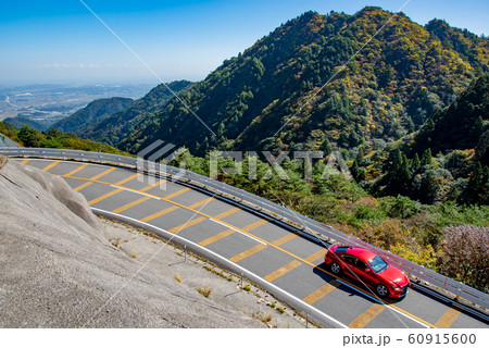 三重県　紅葉の御在所　鈴鹿スカイラインを通り過ぎる赤い自動車 60915600