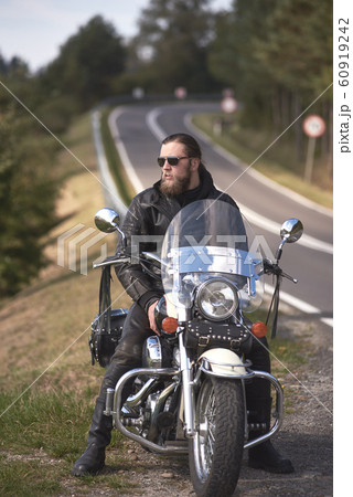 Bearded biker with long hair in black leather jacket sitting on modern motorcycle. Bearded biker with long hair in black leather jacket sitting on modern motorcycle. 60919242