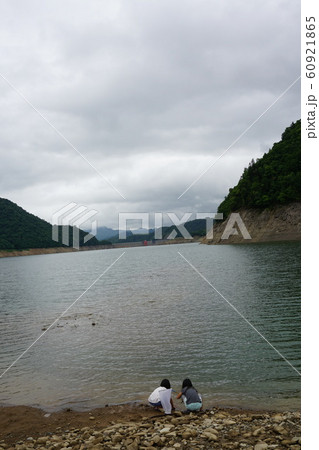 ダムの水辺でしゃがんで遊ぶ姉妹 60921865