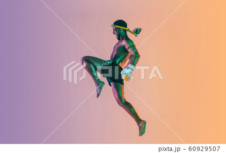 Muay thai. Young man exercising thai boxing on gradient background 60929507