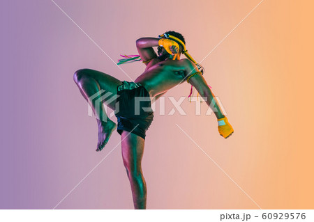 Muay thai. Young man exercising thai boxing on gradient background 60929576