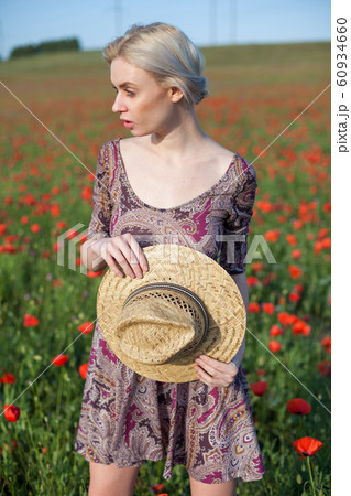 Portrait of a beautiful blonde woman in a hat in a field of red poppies 60934660