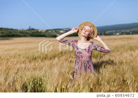 portrait of a beautiful fashionable blonde woman in a hat in a field of ripe wheat 60934672