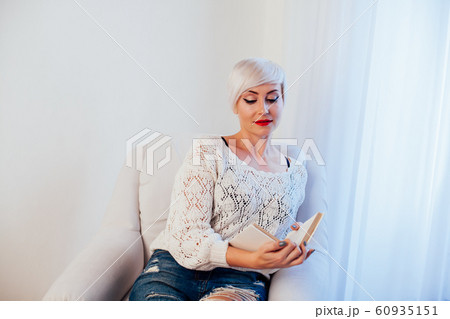 woman reading a book prepared for the exam in a white room 60935151