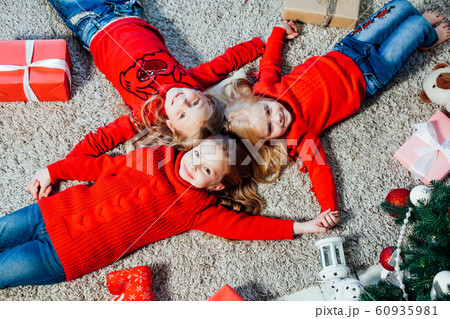 three little girls lie near a Christmas tree with gifts new year holiday three little girls lie near a Christmas tree with gifts new year holiday 60935981