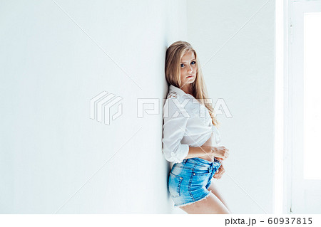 blonde girl with blue eyes in shorts on a white background 60937815