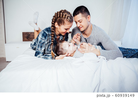 mom dad and son in the morning lying on the bed at home in a good mood mom dad and son in the morning lying on the bed at home in a good mood 60939149