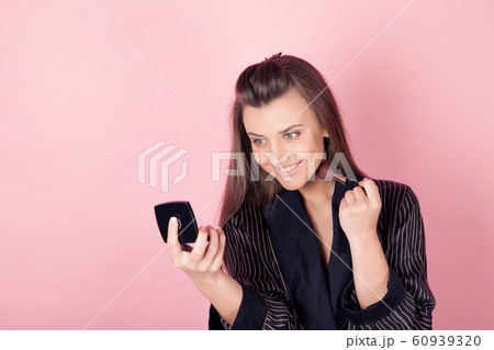 girl in coat makes brush makeup looks in the mirror girl in coat makes brush makeup looks in the mirror 60939320