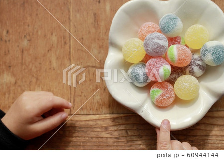 和食器の上のカラフルな飴玉とお皿をつまむ小さな女の子の手 和食器の上のカラフルな飴玉とお皿をつまむ小さな女の子の手 60944144