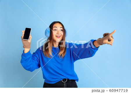 Caucasian woman's portrait isolated on blue studio background, winter theme Caucasian woman's portrait isolated on blue studio background, winter theme 60947719